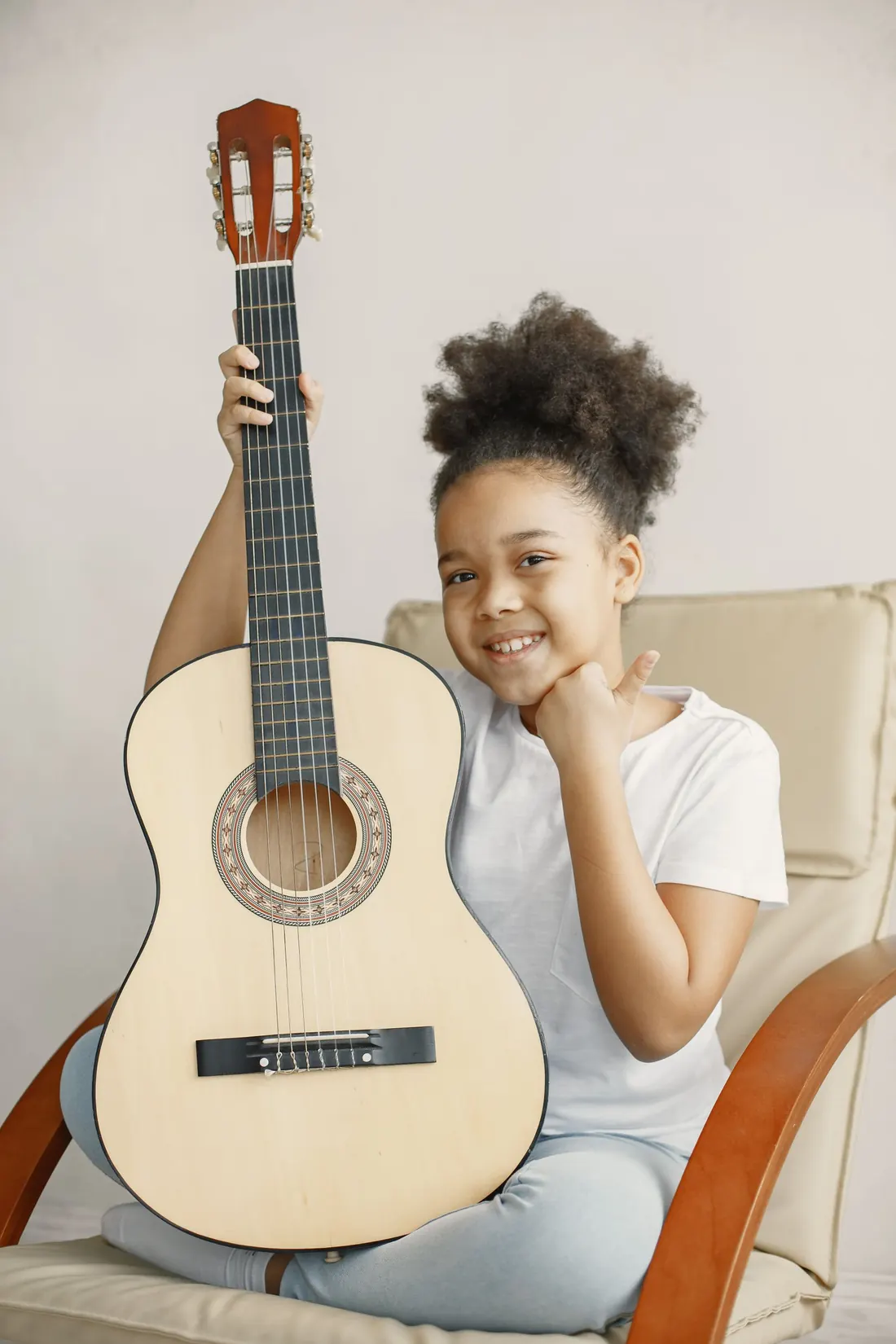 Menina sorrindo, segurando um violão