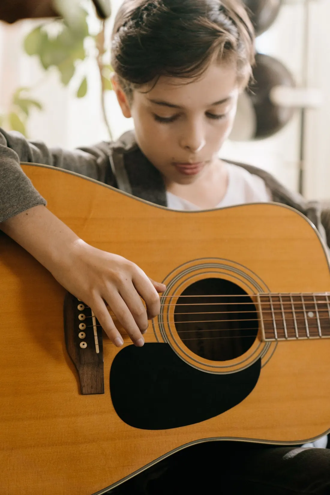 Menino tocando violão, concentrado
