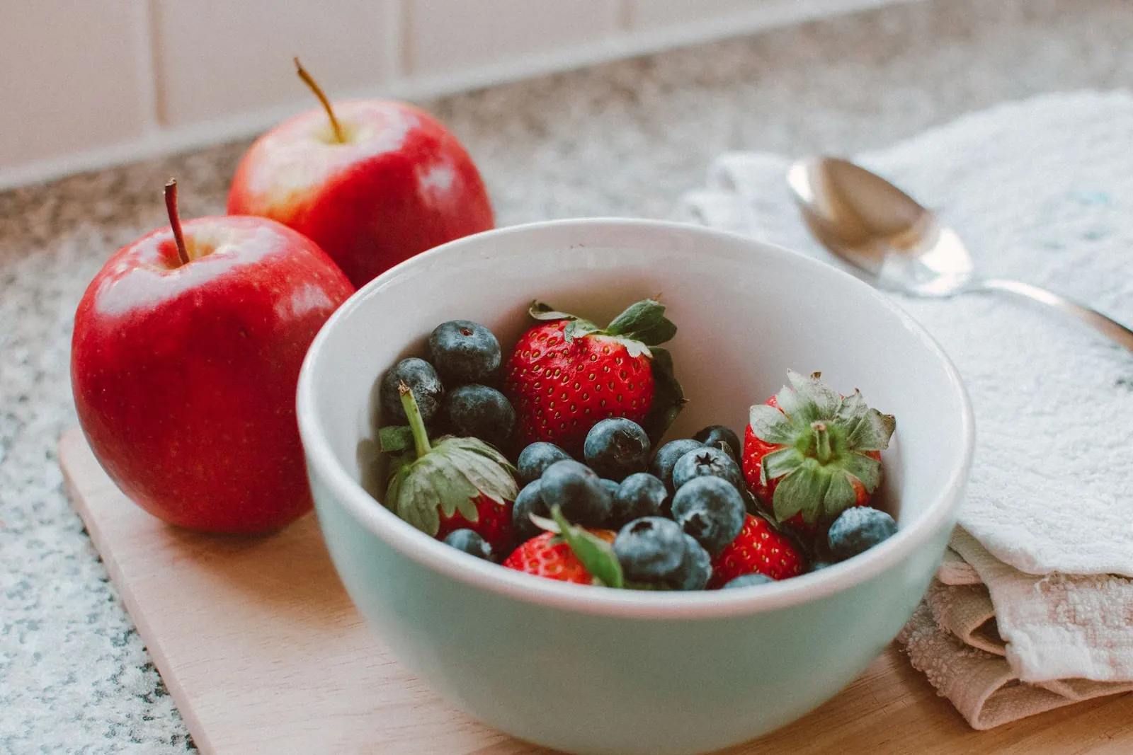 Maçãs e bowl de frutas vermelhas numa cozinha clara