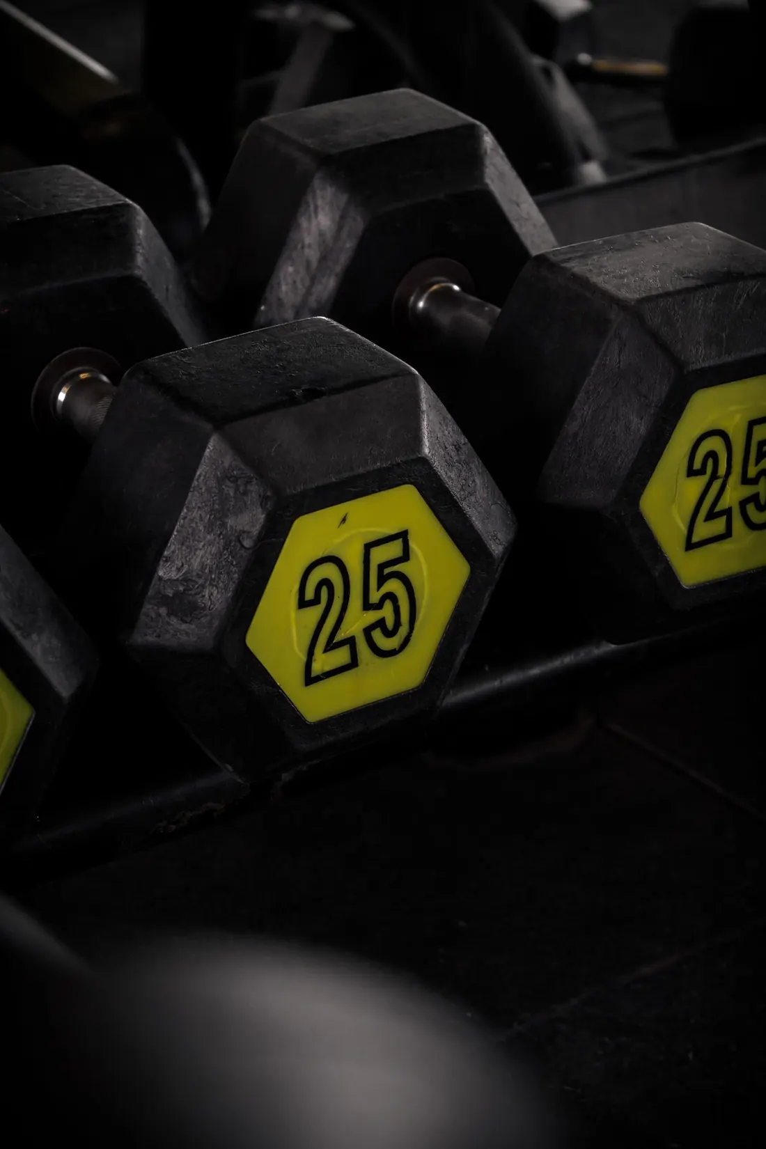 Halteres de 25 kg na prateleira da academia, luz escura